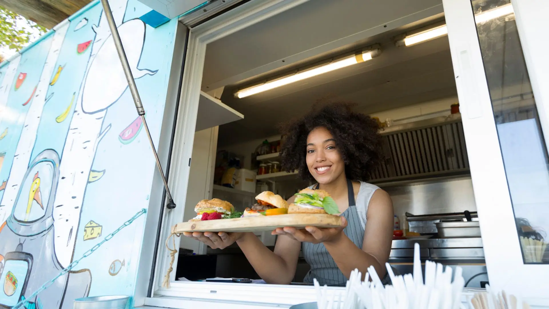 A food truck owner serving hamburgers to customers.