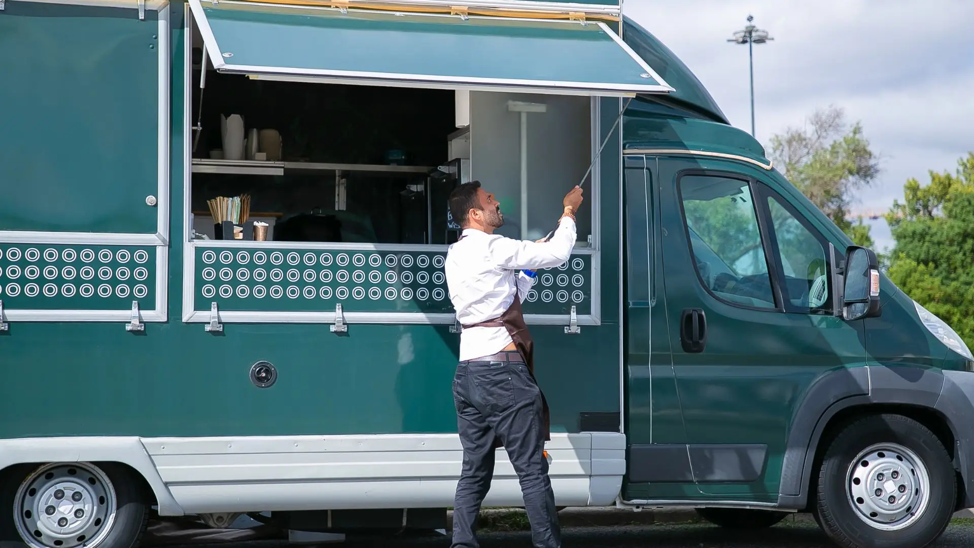 A man setting up his food truck stand for the day.