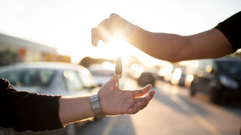 A person handing over a a pair of car keys to another person.