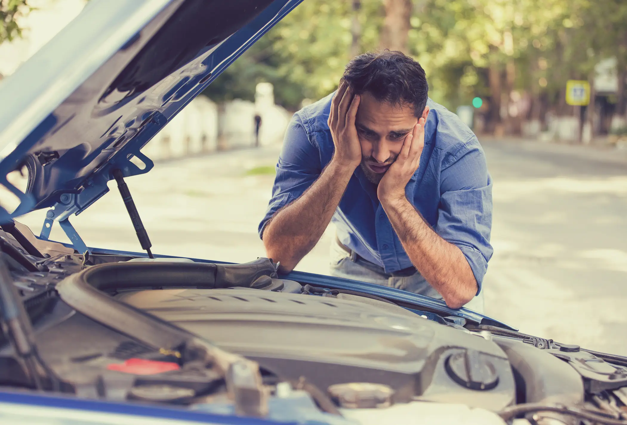 A man looking stumped at his car's engine.