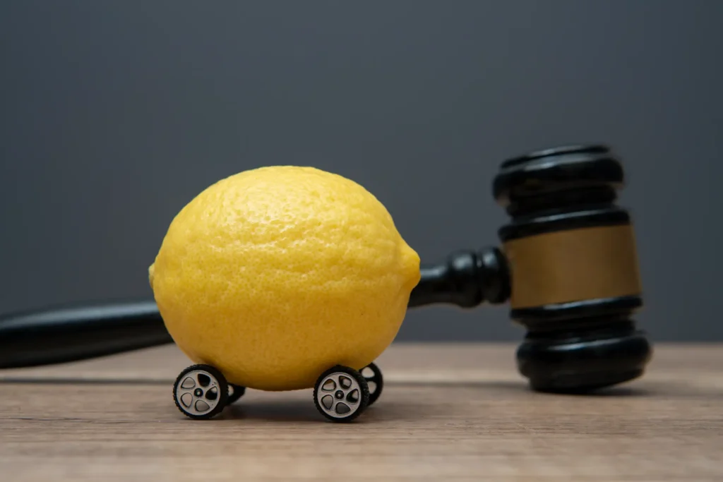 A lemon with wheels next to a gavel.