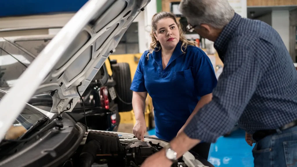 An old man telling a mechanic what is wrong with his car.
